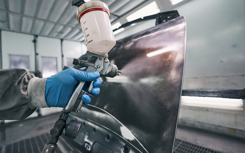 person-covering-car-with-paint-from-spraying-gun-AXSKAFS.jpg